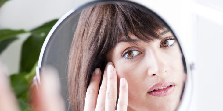 Woman looking at skin in mirror