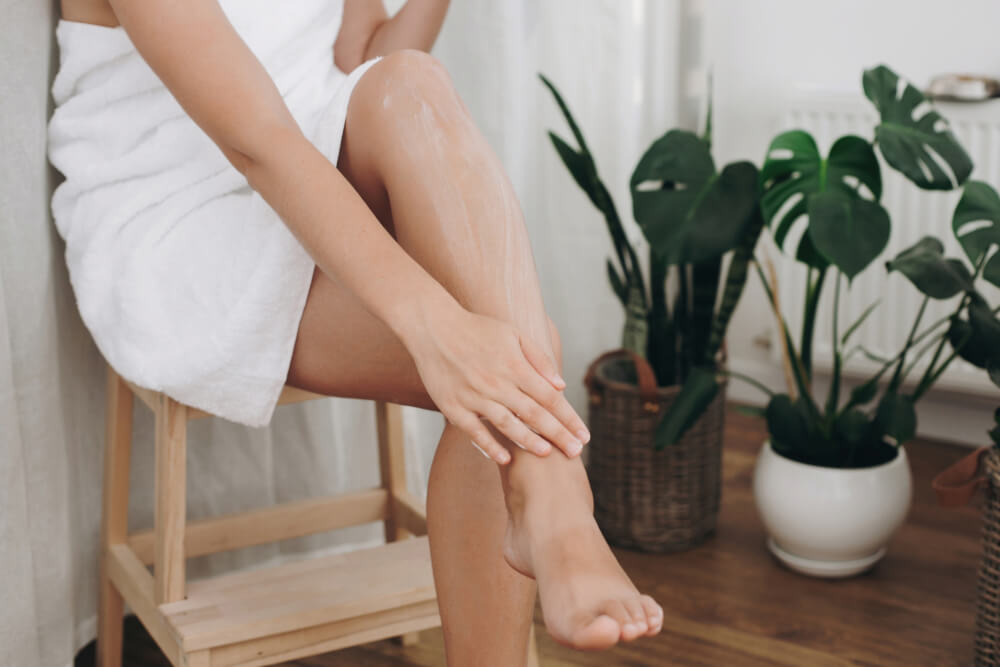 Woman applying body butter to legs