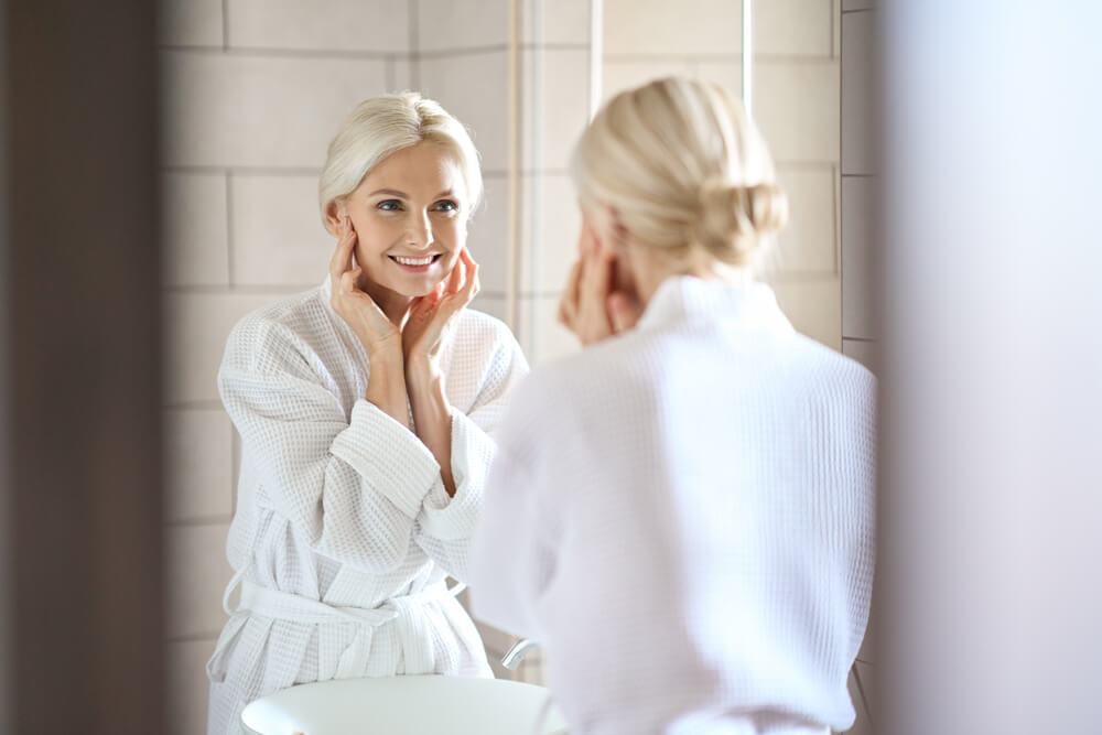 Woman looking at skin in mirror