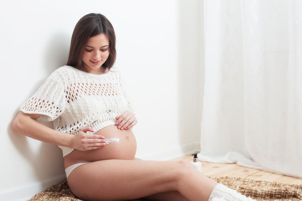 Pregnant woman using stretch mark cream