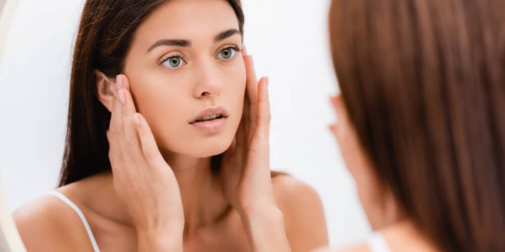 Woman looking at skin in mirror