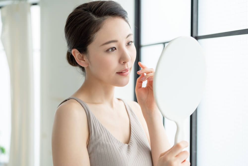 Woman looking at skin in mirror