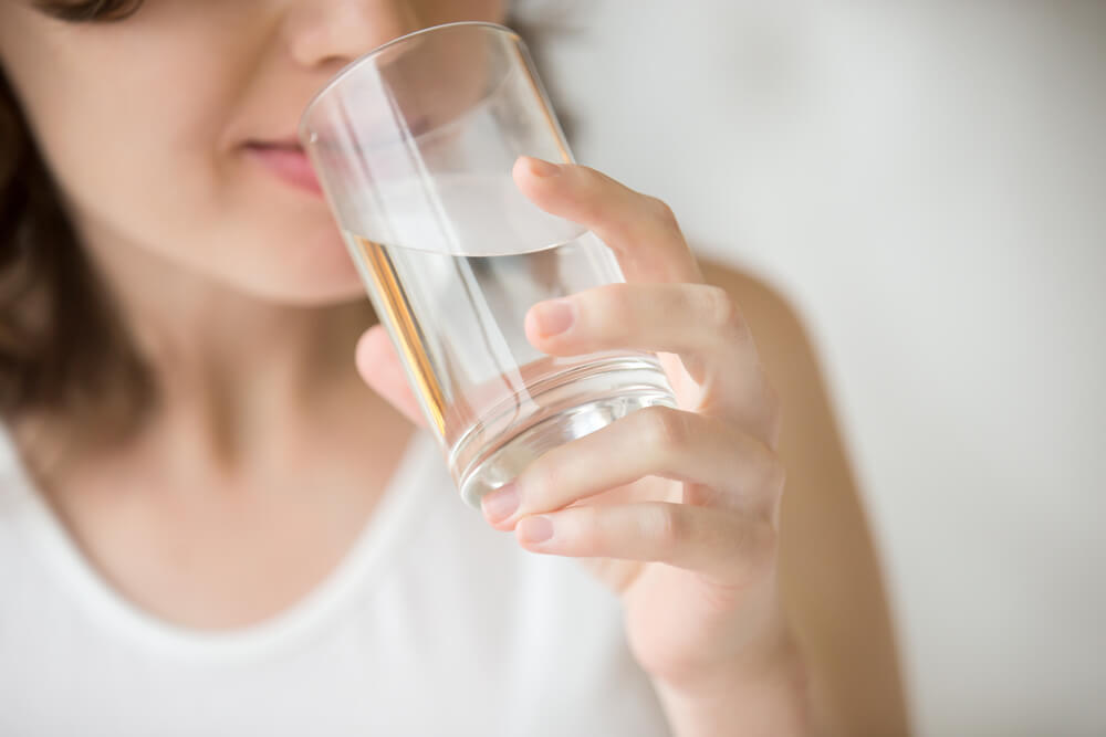 Woman drinking water to help dry skin