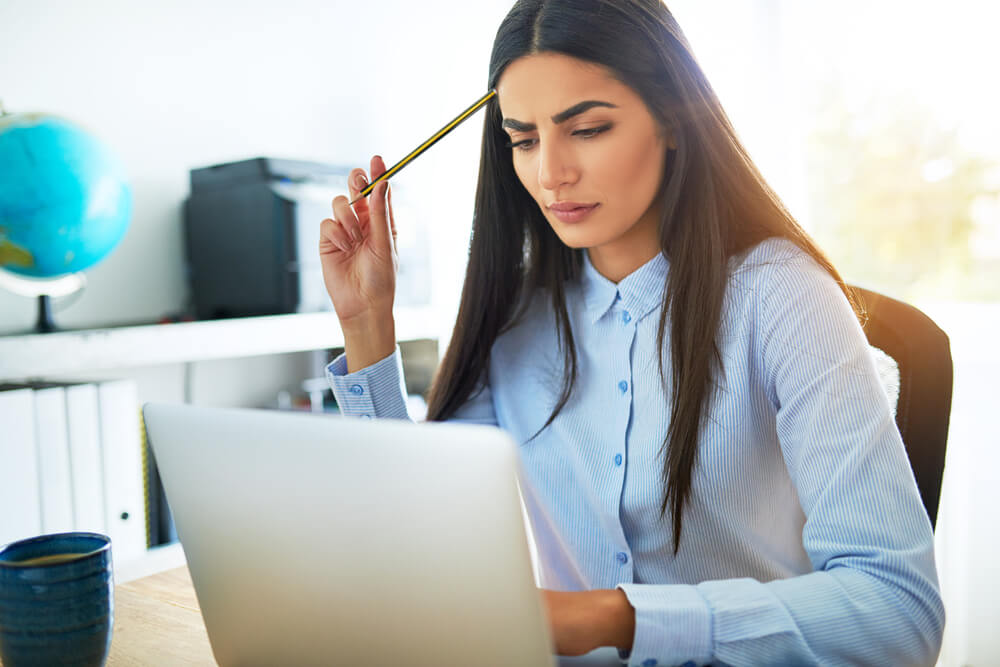 Woman frowning at laptop - De-stress Skin Care Products