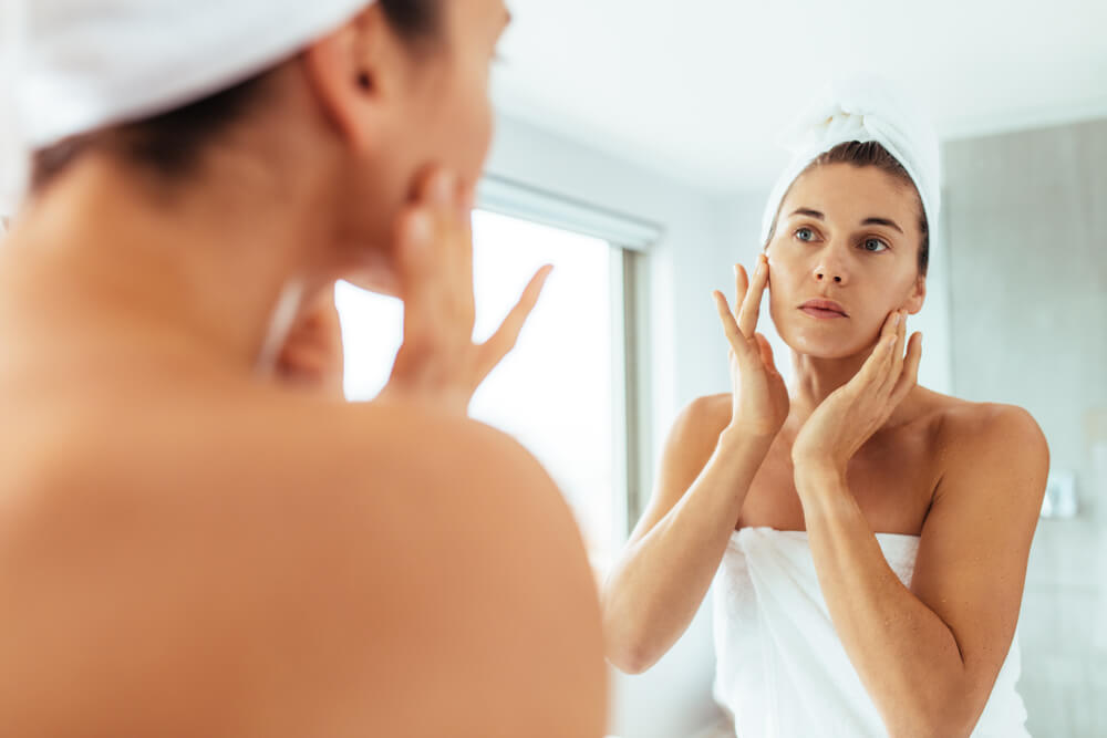 Woman looking at skin in mirror