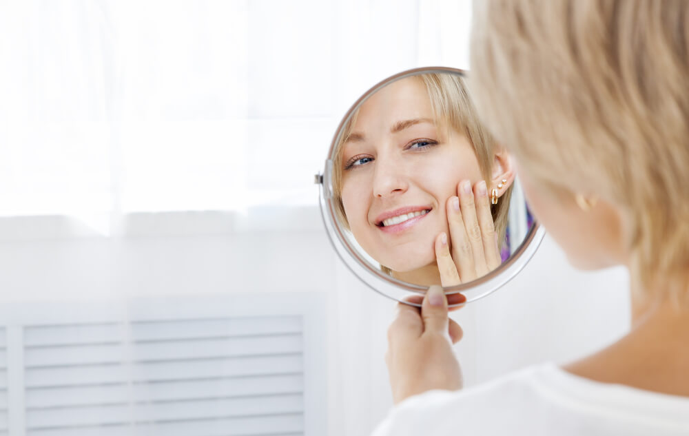 Woman looking at skin in mirror