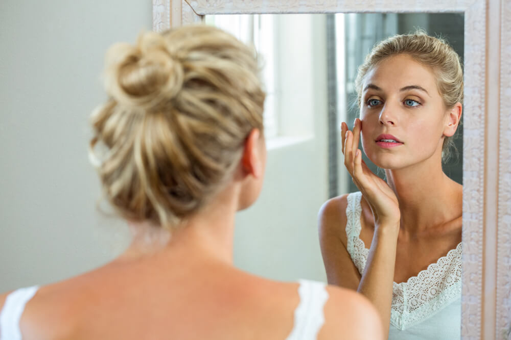 Woman looking at skin in mirror