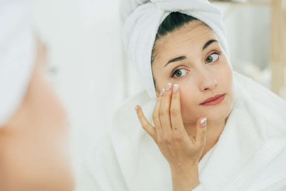 Woman looking at skin in mirror