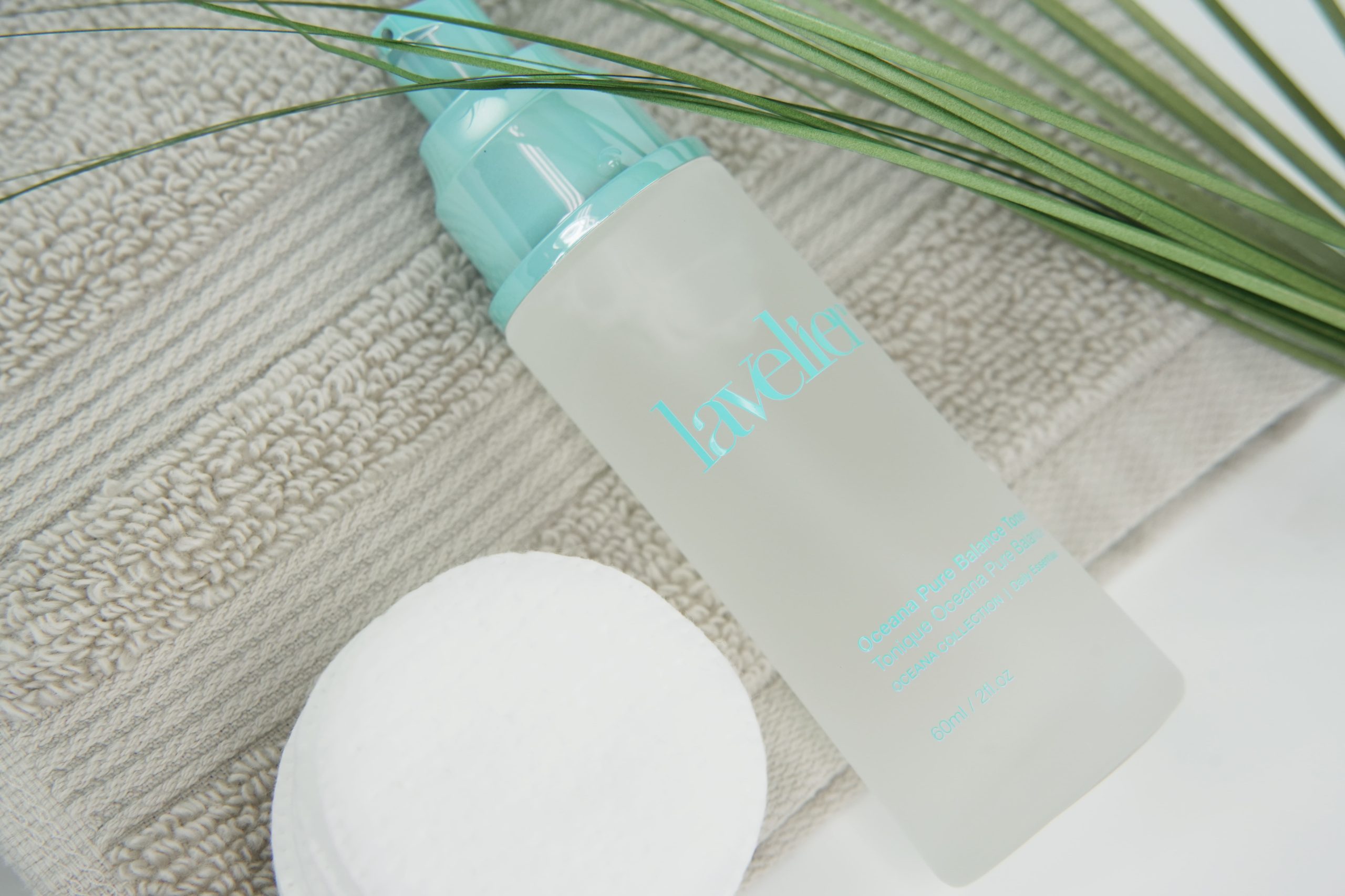 Bottle of Lavelier Oceana Pure Balance Toner lying on a beige towel next to a cotton pad