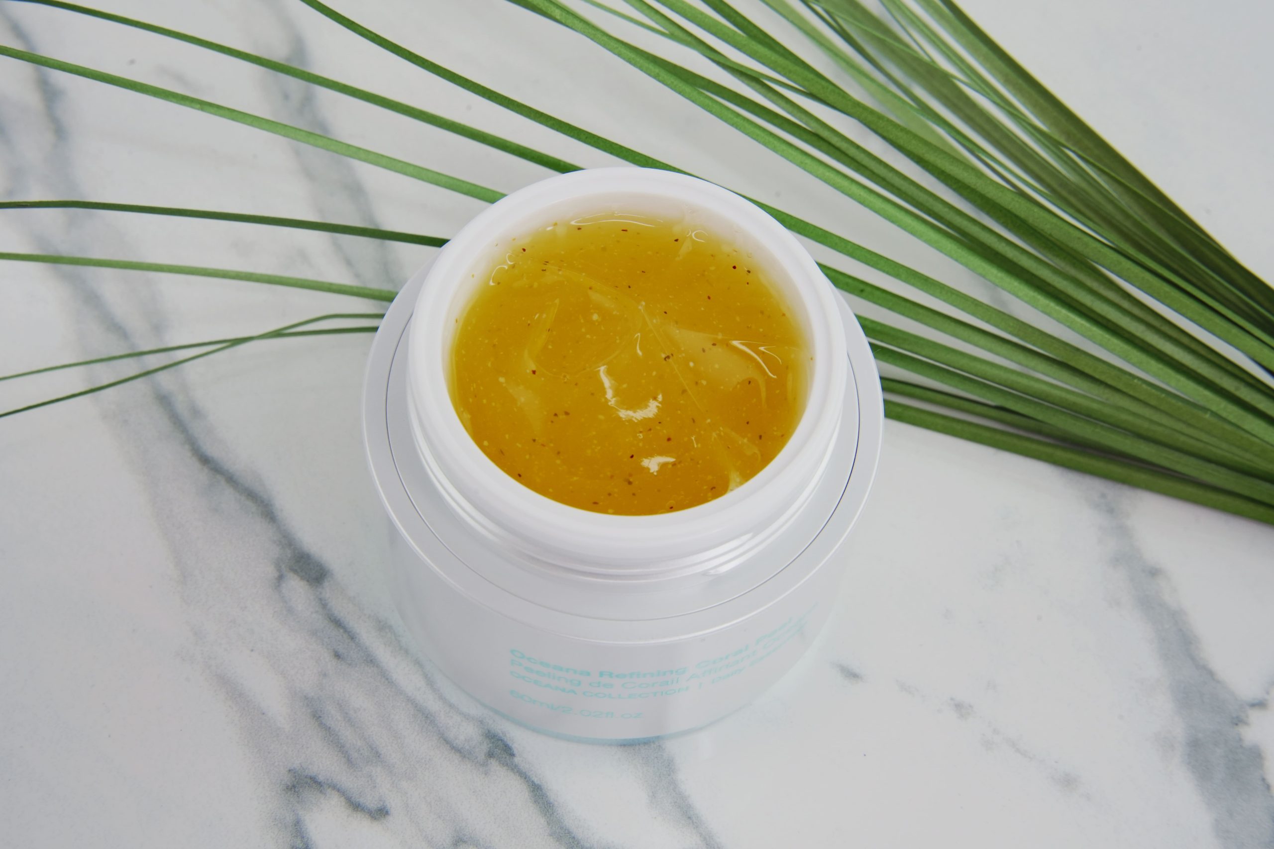Open jar of Lavelier Oceana Refining Coral Peel showing the gel peel inside, on a marble table
