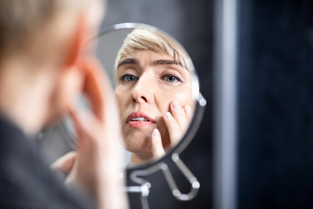 Woman looking at skin in mirror