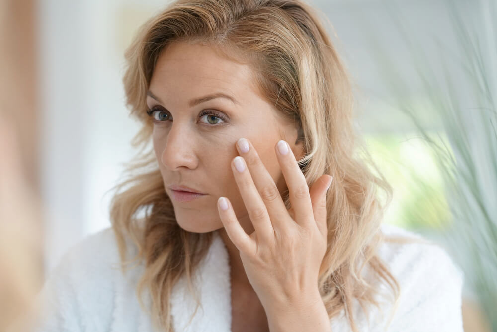 Woman looking at wrinkles in mirror